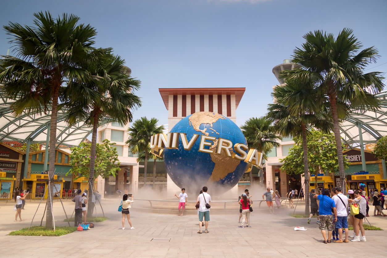 Visitors pose for photos with a revolving Universal Studios globe, outside the entrance to the Universal Studios Singapore theme park at Resorts World Sentosa.