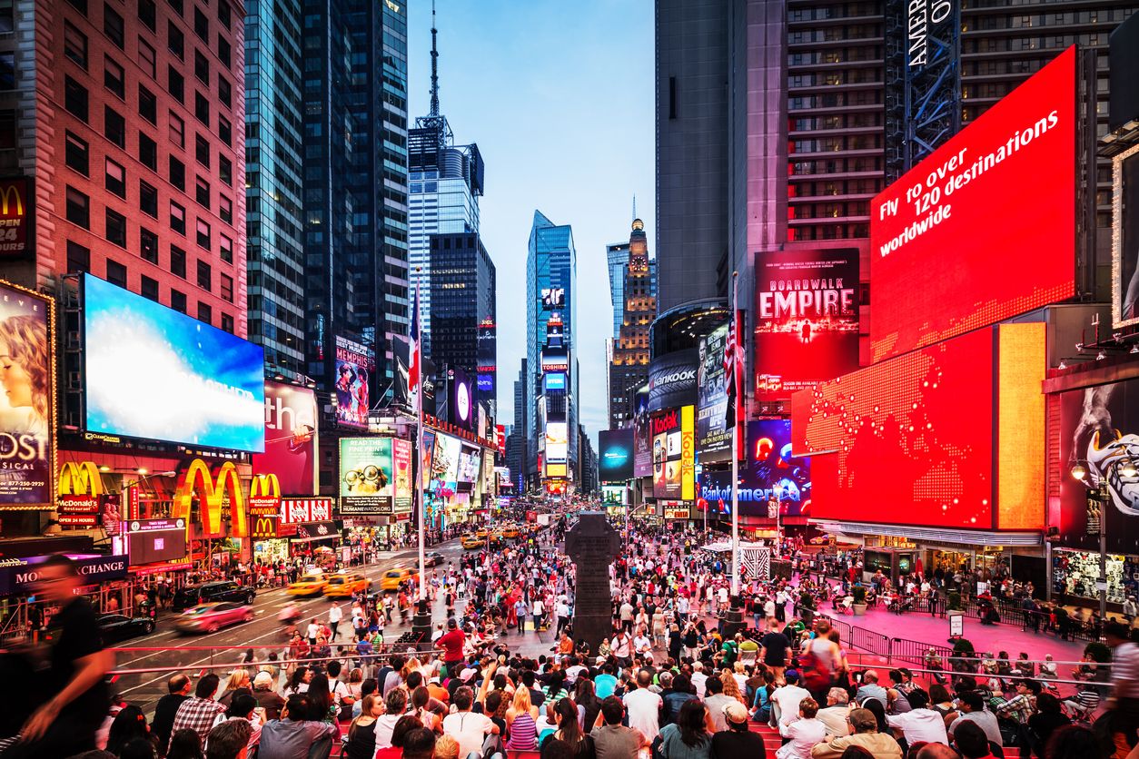 Crowded Times Square at Twilight in New York City, USA with people sitting on the bleachers at the end of the square