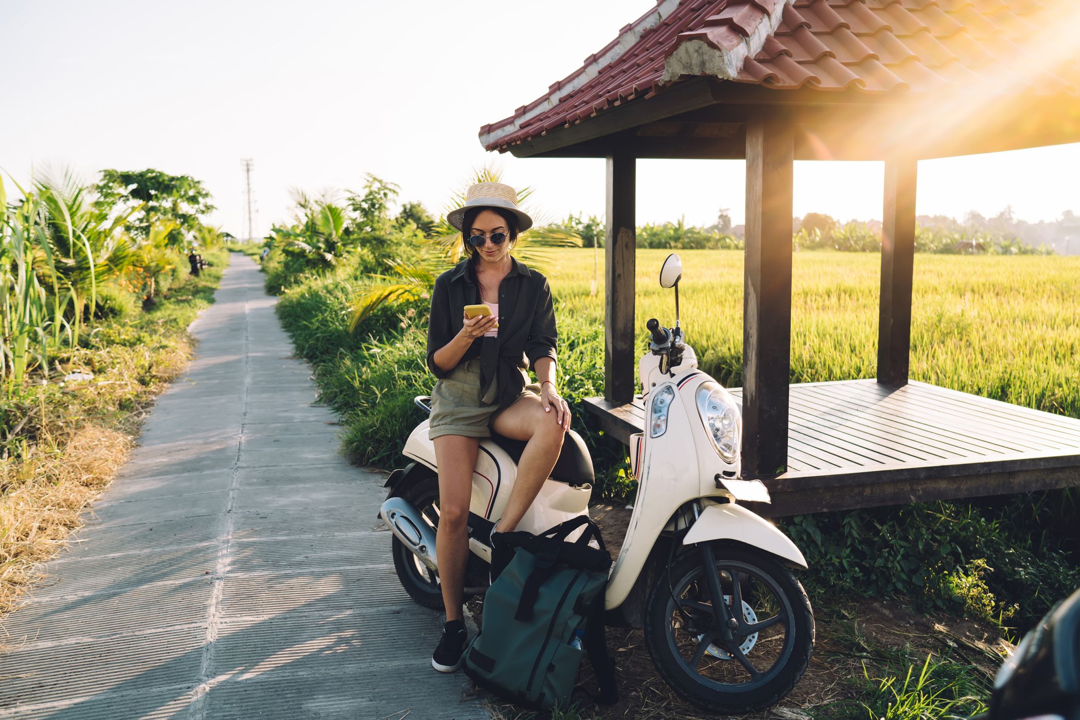 Traveling girl resting on rented moped browsing the internet