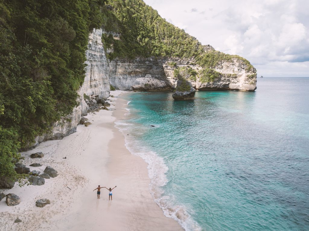 Aerial view of young couple on tropical beach enjoying their vacation in Bali, Indonesia