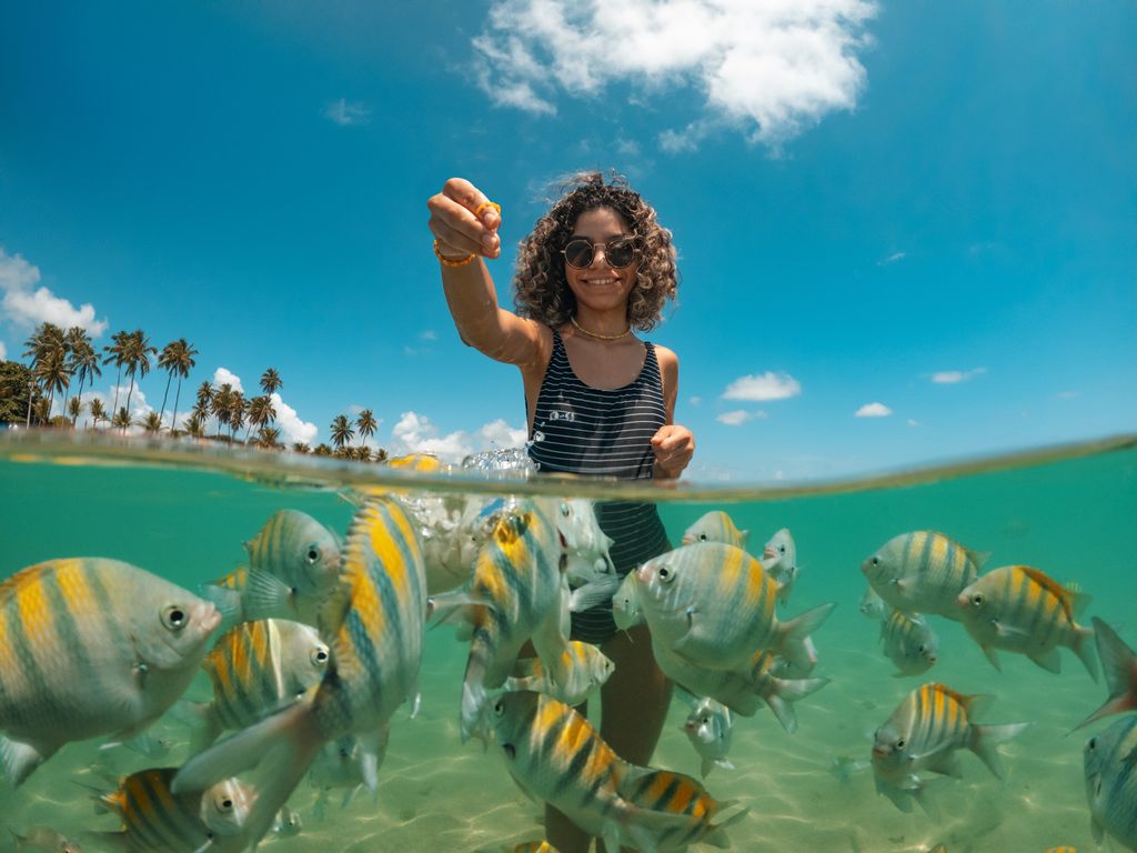 Young woman feeding fish on tropical beach