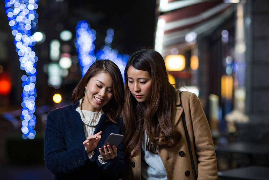 Two women looking at something on a smartphone together