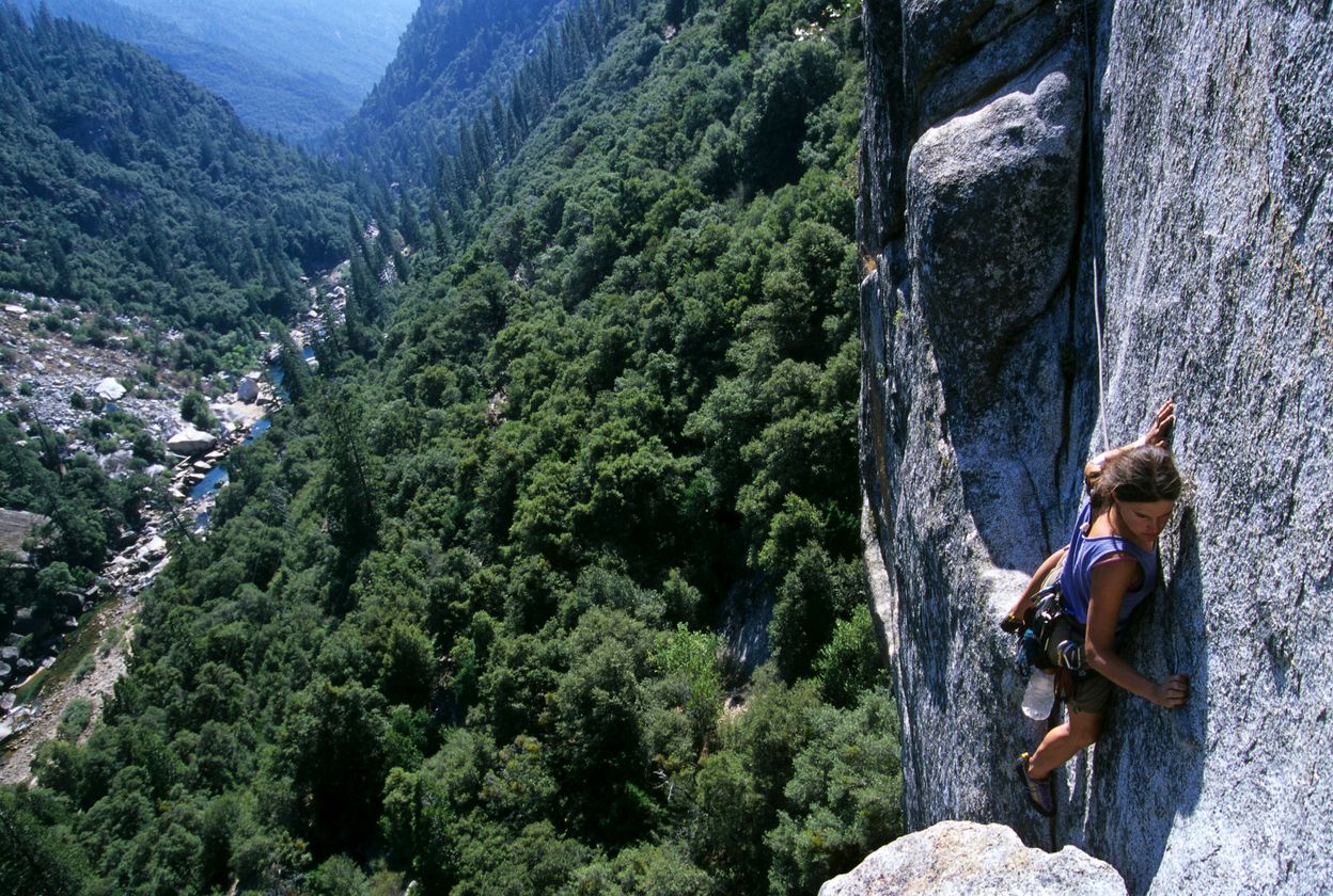 Woman rock climbing high above river in Yosemite National Park, California