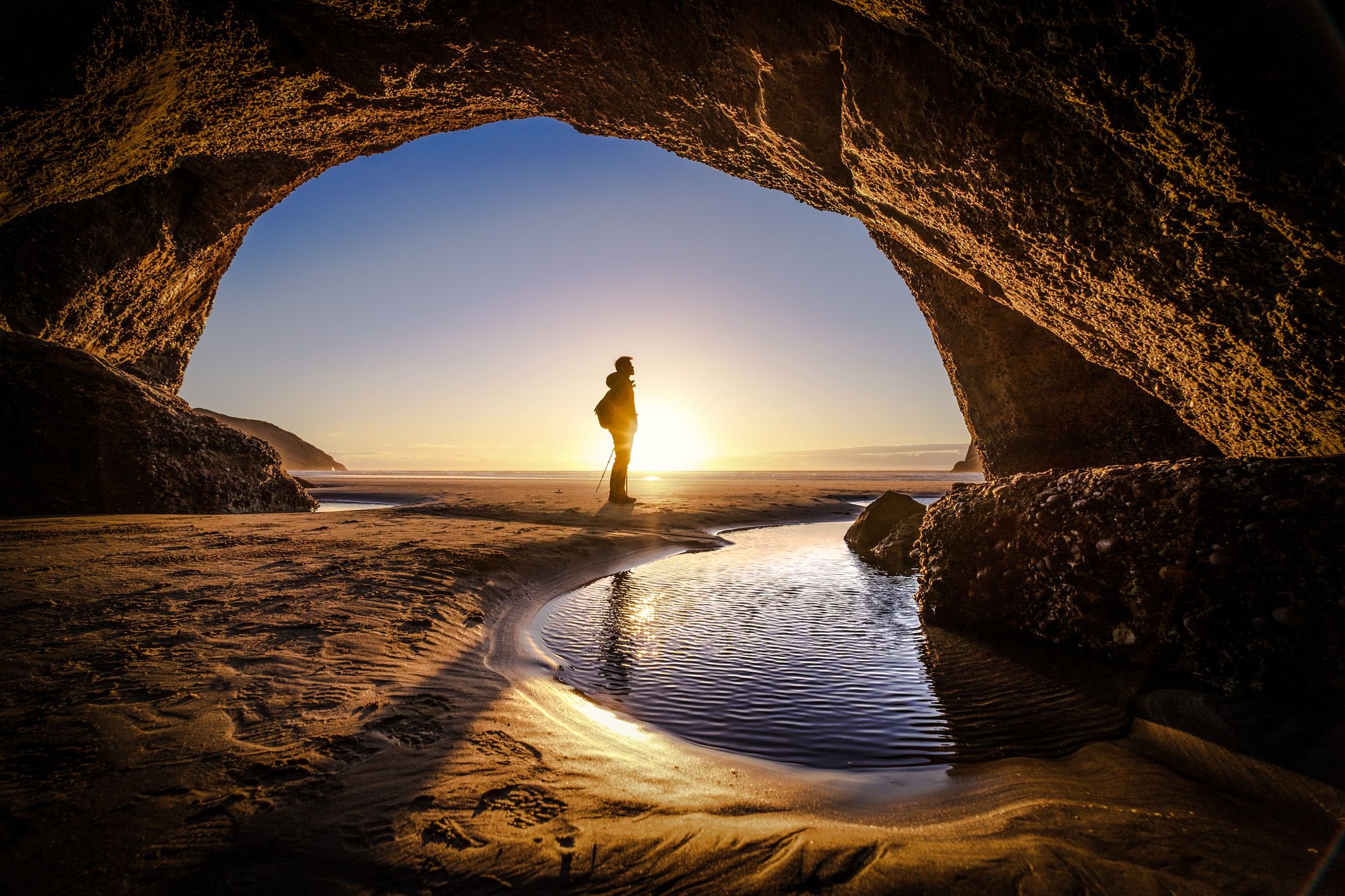 Solo traveler standing in front of a cave exit