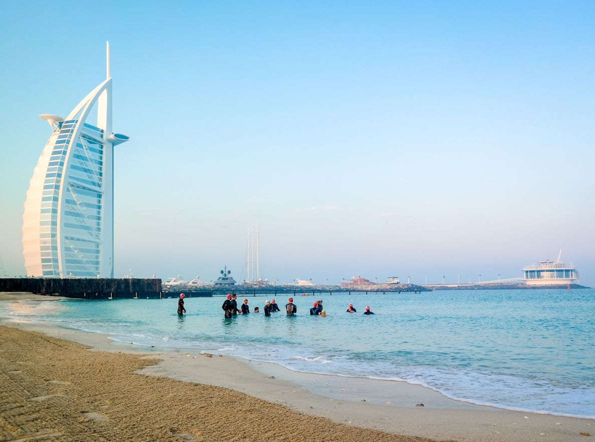 Scuba divers diving under water next to Burj Al Arab on an early morning day in Dubai