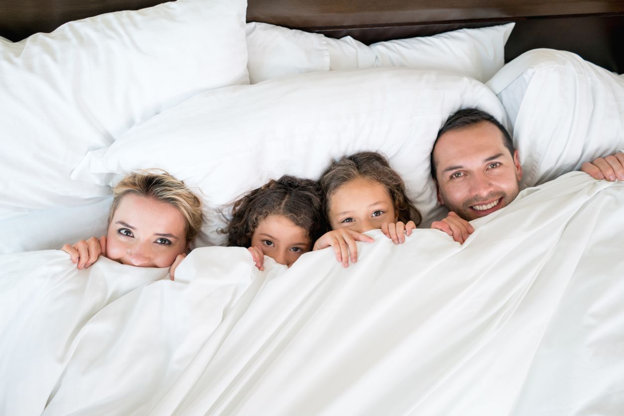 Happy family in bed under the duvet.