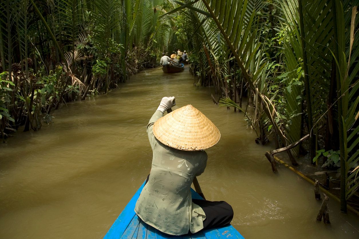 Vietnamese woman rowing a boat in Mekong River in Vietnam