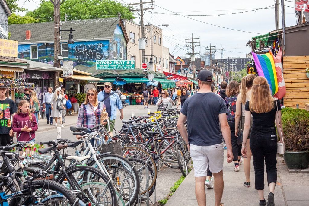 Busy streets of Kensington Market Toronto with pedestrians walking past many bicycles